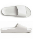Pair of White slide sandals with Archie logo stamped in heel.