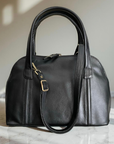 Black leather handbag on a marble surface with a neutral background
