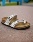 Silver sandal on a textured surface with a blurred playground background