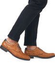Brown derby dress shoes worn with black jeans.