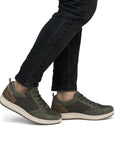 Man in black jeans wearing green casual sneakers.