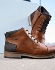 Brown dress boots on display in minimal style background.