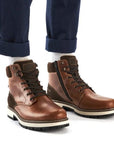 Man in blue rolled up jeans with brown lace-up winter ankle boots on.