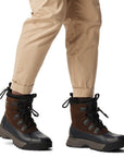 Model wearing Men's Sorel Scout 87 XT Waterproof Winter Boots styled with beige pants, showcasing the boot's ankle height and outdoor-ready design.