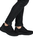 Black slip-on shoes worn with black jeans.