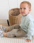 Toddler in front of whicker basket wearing Artic Friends soft sole shoes.