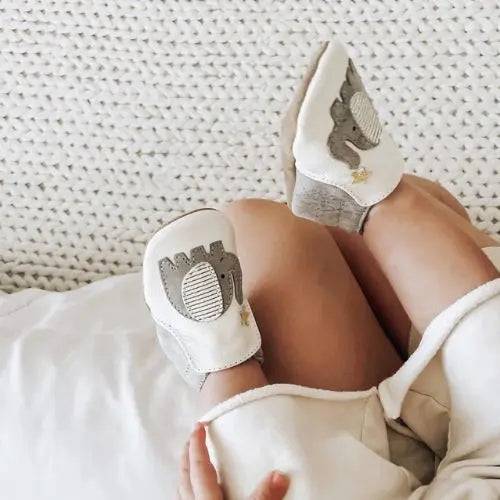 Close-up of baby feet in Robeez Ivory Elephant Soft Soles featuring elephant design and suede soles, perfect for safe and flexible movement.