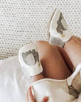 Close-up of baby feet in Robeez Ivory Elephant Soft Soles featuring elephant design and suede soles, perfect for safe and flexible movement.
