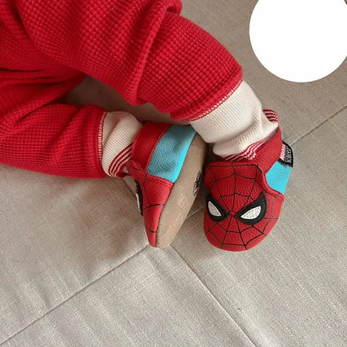 Baby wearing Robeez Marvel Spider-Man soft sole shoes, showcasing flexible fit and superhero design for stylish infant footwear.