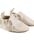 Gold glittery baby shoes with brown outsoles and stars on the heels.
