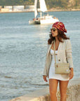 Woman wearing the beige Heritage Anti-Theft Crossbody Bag while walking by the sea, perfect for stylish and secure travel adventures.