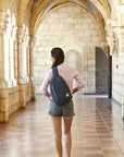 Woman wearing Travelon Anti-Theft Sling Bag in historic setting, showcasing its compact, stylish, and secure design for travel adventures.