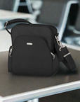 Black Travelon Anti-Theft Classic Travel Bag placed on a table in an airport setting, showcasing its compact and secure design for travelers.
