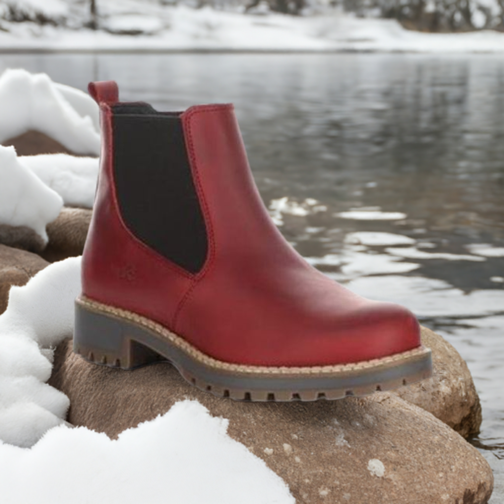 Red Bos&Co Corra Chelsea winter boot for women displayed outdoors on snowy rocks, showcasing waterproof leather and cold-rated wool lining.