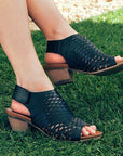 Woman with legs crossed wearing the Lacey sandal in black.