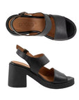 Top and profile view of Myla heeled sandal. Asymmetrical black leather upper, brown leather footbed, and black outsole.