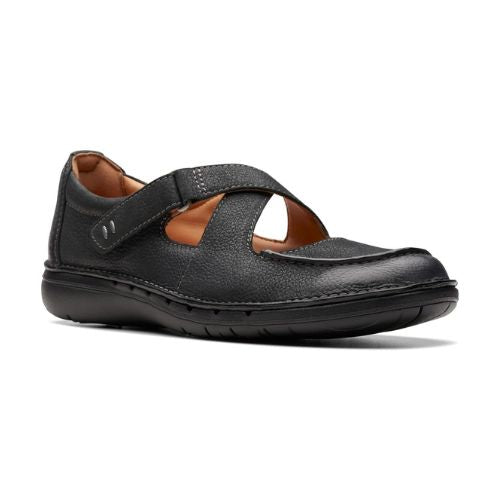 Black leather Mary Jane flat with black outsole. Features a crisscross velcro strap across the instep.