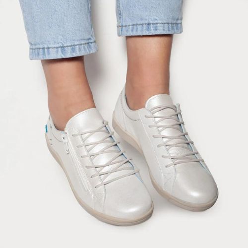 Model wearing white Cloud Aika women's sneakers with soft Italian leather and side zipper, styled with light denim jeans.