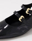 Close-up of black Django & Juliette Viraz Slingback Heels showing glossy leather and heart-shaped gold buckle strap details.