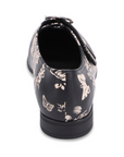 Heel of Black dress shoe with brown floral pattern and two velcro straps with detail buckles.