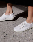 Woman taking a step onto pavement wearing the Ecco Soft 2.0 white Sneakers.