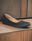 Eco-friendly black El Naturalista N5300 women's ballet flat displayed on wooden surface, featuring soft leather and cushioned footbed.