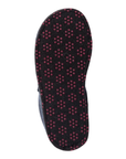 Outsole of a black slipper with repeating pattern of small red circular dots (traction dots).
