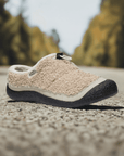 Women's KEEN Howser III Slide Clog in beige fleece shown on a road, highlighting its hybrid comfort for both indoor and outdoor use.