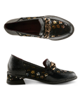 Pair of glossy black leather loafers with dark yellow and blue floral pattern on the side panels, a decorative burnished gold metal rose on chain embellishment on the vamp, and black sculptured low block heel.