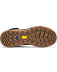 The outsole of a brown rugged boot, showing deep tread patterns and a small yellow Vibram logo in the center.