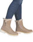Beige winter boots with fur trim worn with blue jeans.