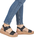 Black sandals with cork platforms worn with blue jeans.