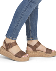Brown sandals with cork platforms worn with rolled-up blue jeans.