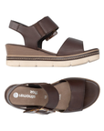 Pair of Dark Brown backstrap platform sandals with oversized decorative buckle, two Velcro straps, Remonte logo'd footbed, a faux wood grain wedge midsole and an off-white outsole.