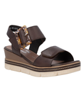 Dark Brown backstrap platform sandal with oversized decorative buckle, two Velcro straps, Remonte logo'd footbed, a faux wood grain wedge midsole and an off-white outsole.