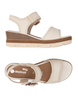 Pair of Beige wedge sandals with brown buckle, accent zig-zag stitching, tan Remonte logo'd footbed and off-white outsole.