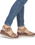 Brown wedge sandals worn with blue jeans.