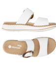 Pair of White slide sandals with two Velcro straps, marbled circle buckle, tan Remonte logo'd footbed, and a white platform with beige accents.
