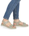 Green backstrap sandals with buckle detail worn with blue jeans.