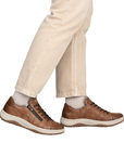 Brown leather shoes worn with beige pants.