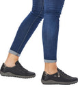 Model wearing black Remonte R1402 lace-up sneakers with jeans, showcasing stylish waterproof footwear for women on the go.