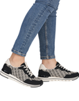 Black and white patterned sneakers worn with blue jeans.