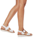 Model walking in Rieker R6853 Backstrap Sandal in white, demonstrating stylish comfort and adjustable fit for casual summer fashion.