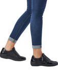 Model wearing black Remonte R7637 Lace-Up Sneakers with stretch material, styled with rolled denim for casual comfort.