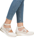 Model wearing off-white Remonte D2411 women's sneaker shoes with jeans, showcasing stylish wedge heel and supportive ankle strap design.