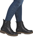 Black leather combat boots worn with blue jeans.