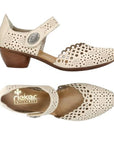 Pair of Beige heeled open sided Mary-Janes with Velcro ankle strap, floral pattern, decorative perforations and a low stacked heel.