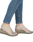 Silver wedge sandals worn with rolled-up blue jeans.