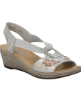 Silver wedge sandal with floral embellishments, silver medallion, and faux espadrille midsole.