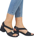 Model wearing Women's Rieker 64683 Sling-Back Heel with jeans, highlighting the elegant floral design and silver medallion accent.
